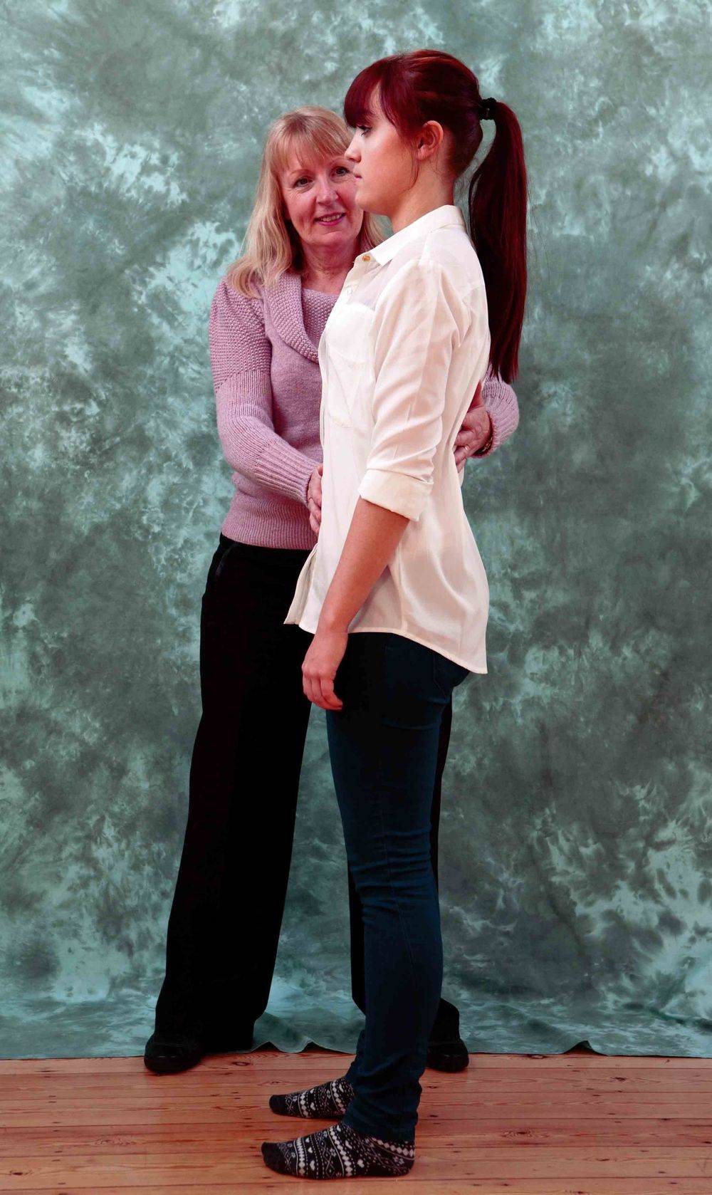 Adele standing directly behind the pupil, both upright, her hands at the pupil's neck and back